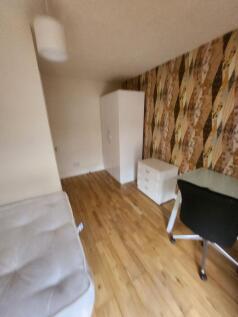 A cozy bedroom featuring a white wardrobe, a sm...