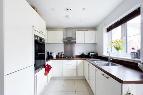 Bright modern kitchen with white cabinetry, dar...