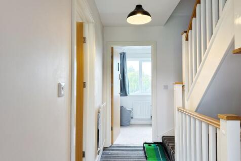 Bright, well-maintained hallway with striped ru...