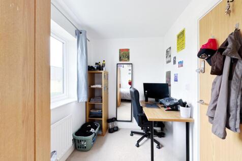 Bright single bedroom with a window-dressed bay...