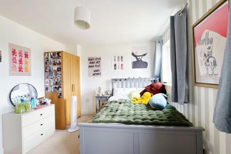 Bright, neatly styled bedroom with a painted be...