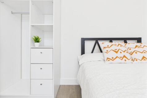 A bright, modern bedroom featuring a neatly mad...