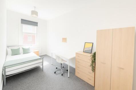 A bright, clean bedroom featuring a comfortable...