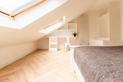 Bright and airy bedroom featuring large skyligh...