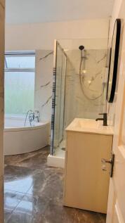 A modern bathroom featuring a spacious shower e...