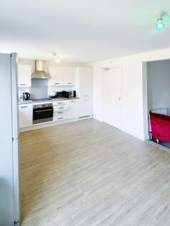 Bright, modern open-plan kitchen with white cab...