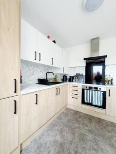 Bright modern kitchen with light wood lower cab...