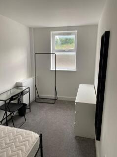 A bright and tidy student room featuring a wind...
