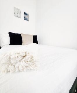 Bright, minimalist double bedroom with crisp wh...