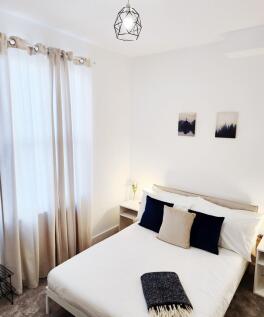 Bright, neatly staged double bedroom with a cri...