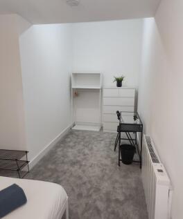 A bright and minimalist bedroom featuring white...
