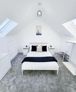 Bright, modern attic master bedroom with a doub...