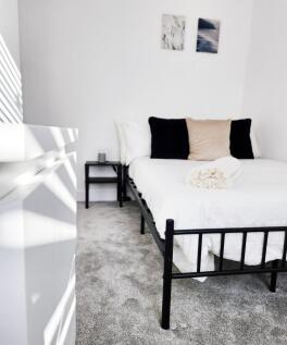 Bright, minimalist bedroom with a crisp white b...