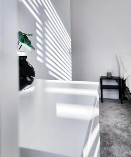 Bright, minimalist bedroom with soft grey carpe...