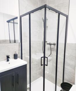 Modern tiled bathroom with a framed glass corne...