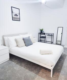 Bright, modern double bedroom with a white bedf...