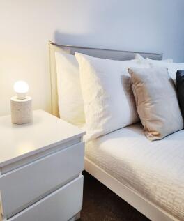Bright, neatly made bedroom corner with a moder...