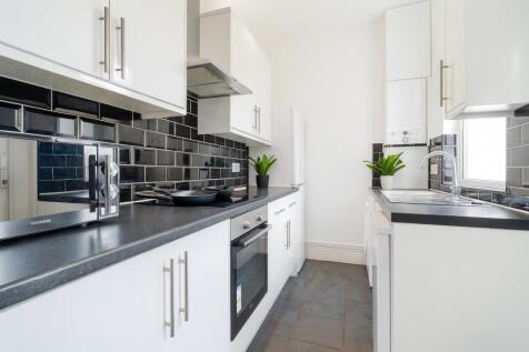 Modern kitchen with sleek white cabinetry, blac...