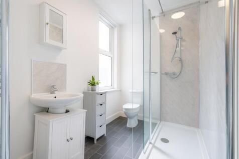 Bright and modern bathroom featuring a glass-en...