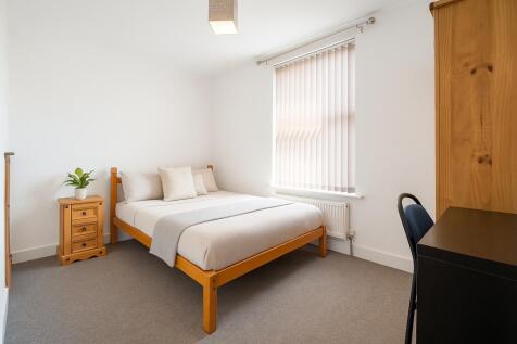 A bright and tidy bedroom featuring a wooden be...