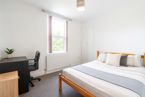 A bright and clean bedroom featuring a comforta...