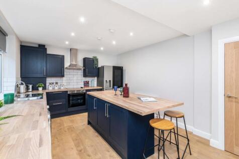 Modern and well-lit kitchen with sleek dark cab...