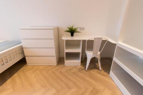 Bright, tidy bedroom corner with white furnitur...