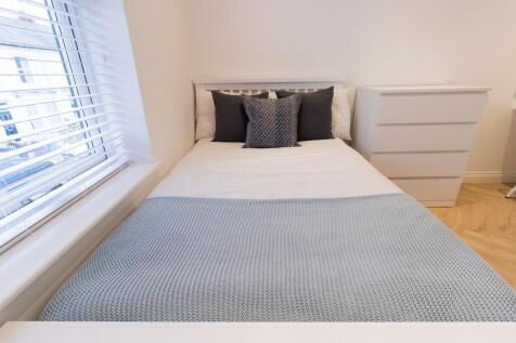 Bright, tidy bedroom with a neatly made bed, pa...