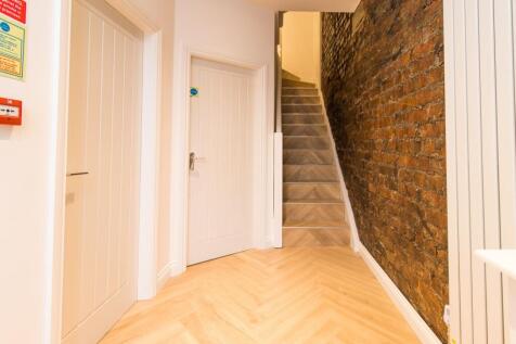 Bright, modern hallway with chevron wood floori...