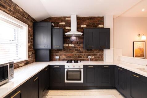 Stylish U-shaped kitchen with dark fitted cabin...