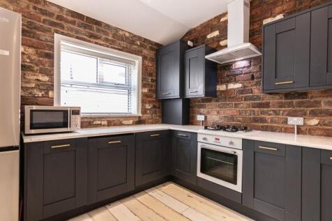 Modern kitchen with exposed brick walls, dark s...