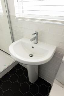 Bright, modern bathroom with a white pedestal s...