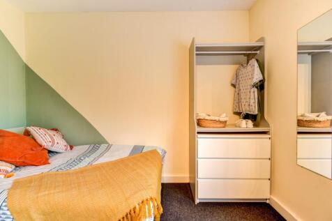 A cozy bedroom featuring a neatly made bed with...