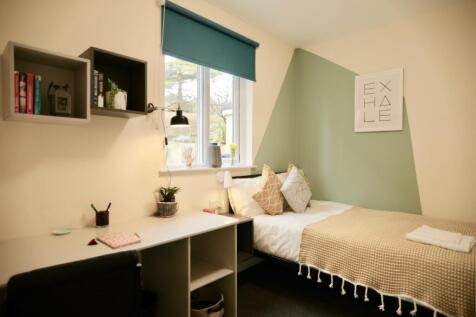 A cozy single bedroom featuring a window with a...