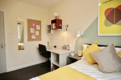 A bright and cozy bedroom featuring a neatly ma...