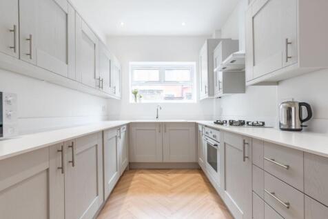 Bright, modern galley kitchen with neutral shak...
