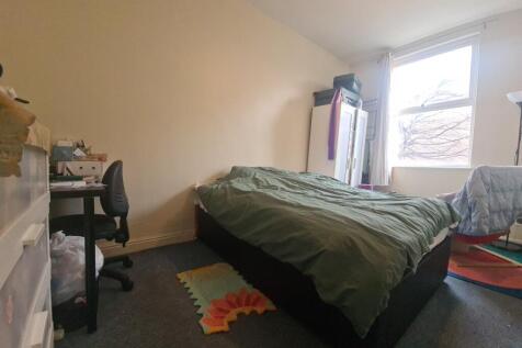 A modest bedroom featuring a bed and a window t...