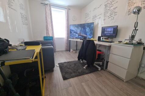 A cozy student bedroom featuring a desk with a ...
