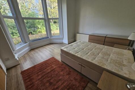 A bright, sunny bedroom featuring a large windo...