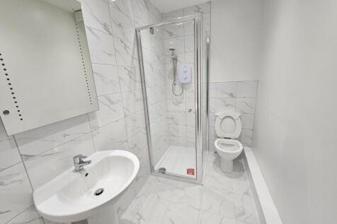 A clean, modern bathroom with a walk-in shower,...