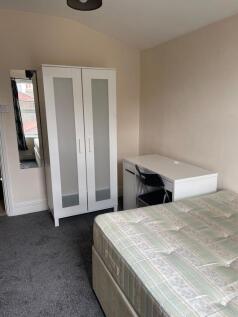 A well-lit bedroom featuring a single bed, a wh...