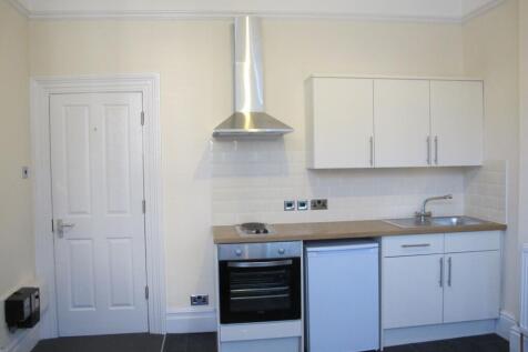 Bright, modern kitchenette with white cabinets,...