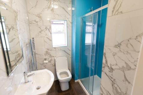 Modern bathroom with white marble-effect tiled ...