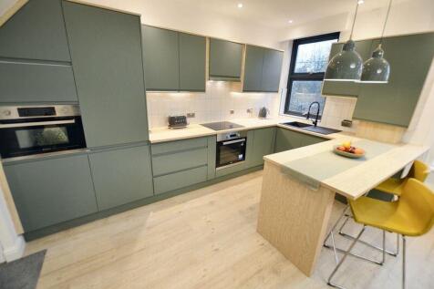 Contemporary fitted kitchen with matte green ca...