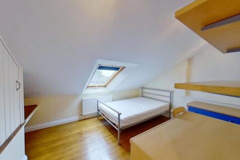 Bright attic double bedroom with a metal bed fr...