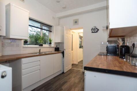 Modern galley kitchen with white cabinetry, woo...