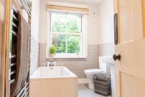 Bright, modern bathroom with a white bathtub be...