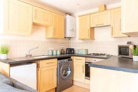 Bright modern kitchen with light wood cabinets,...