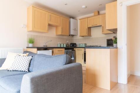 Bright open-plan kitchen with light wood cabine...