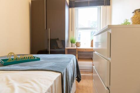 Bright, tidy bedroom with a neatly made bed, mo...